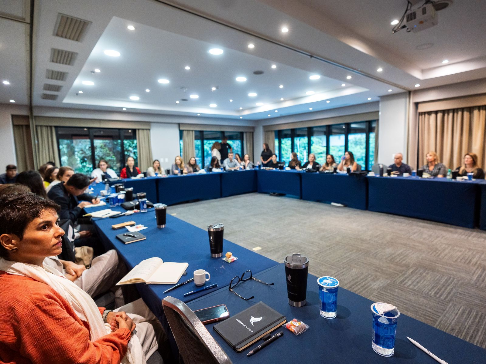 Participantes sentados ao redor de uma mesa em formato de U durante o encontro presencial